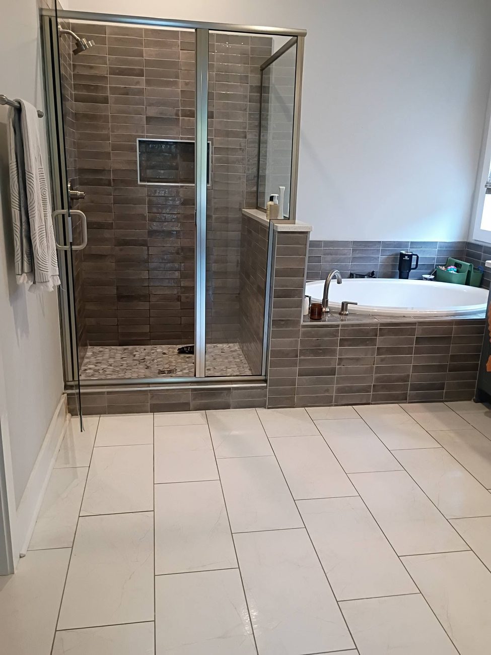 A clean bathroom with a tub, shower and tiled floor