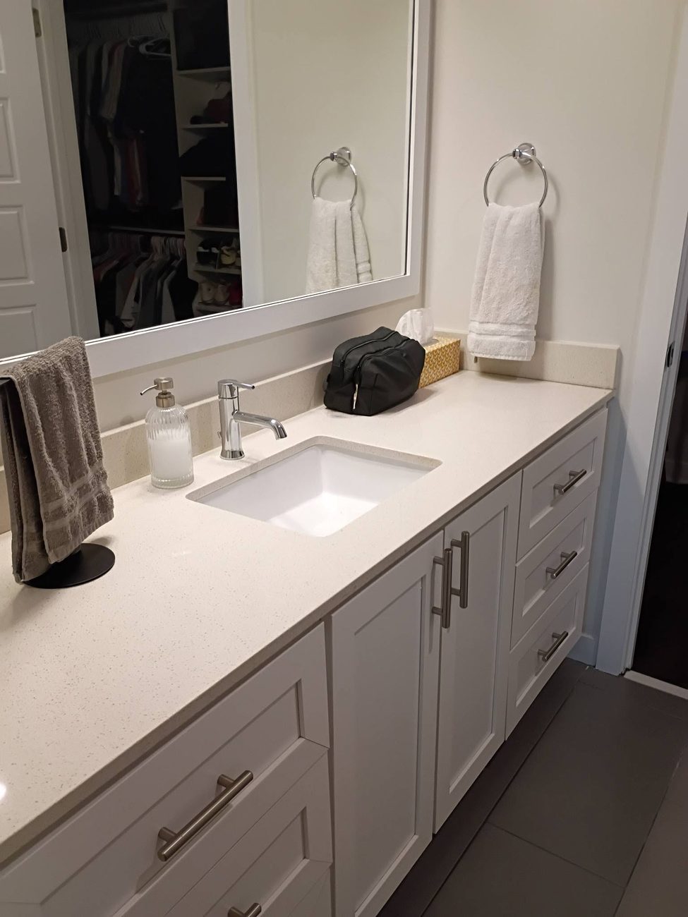 A bathroom vanity with a polished counter and mirror